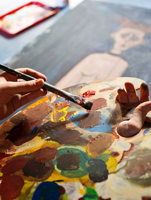 Artist mixing colours on a palette while painting representing the Explorer archetype of creativity and discovery