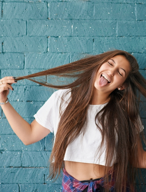 Smiling young woman playfully pulling her hair and sticking out tongue representing the Jester archetype of humour and quirkiness