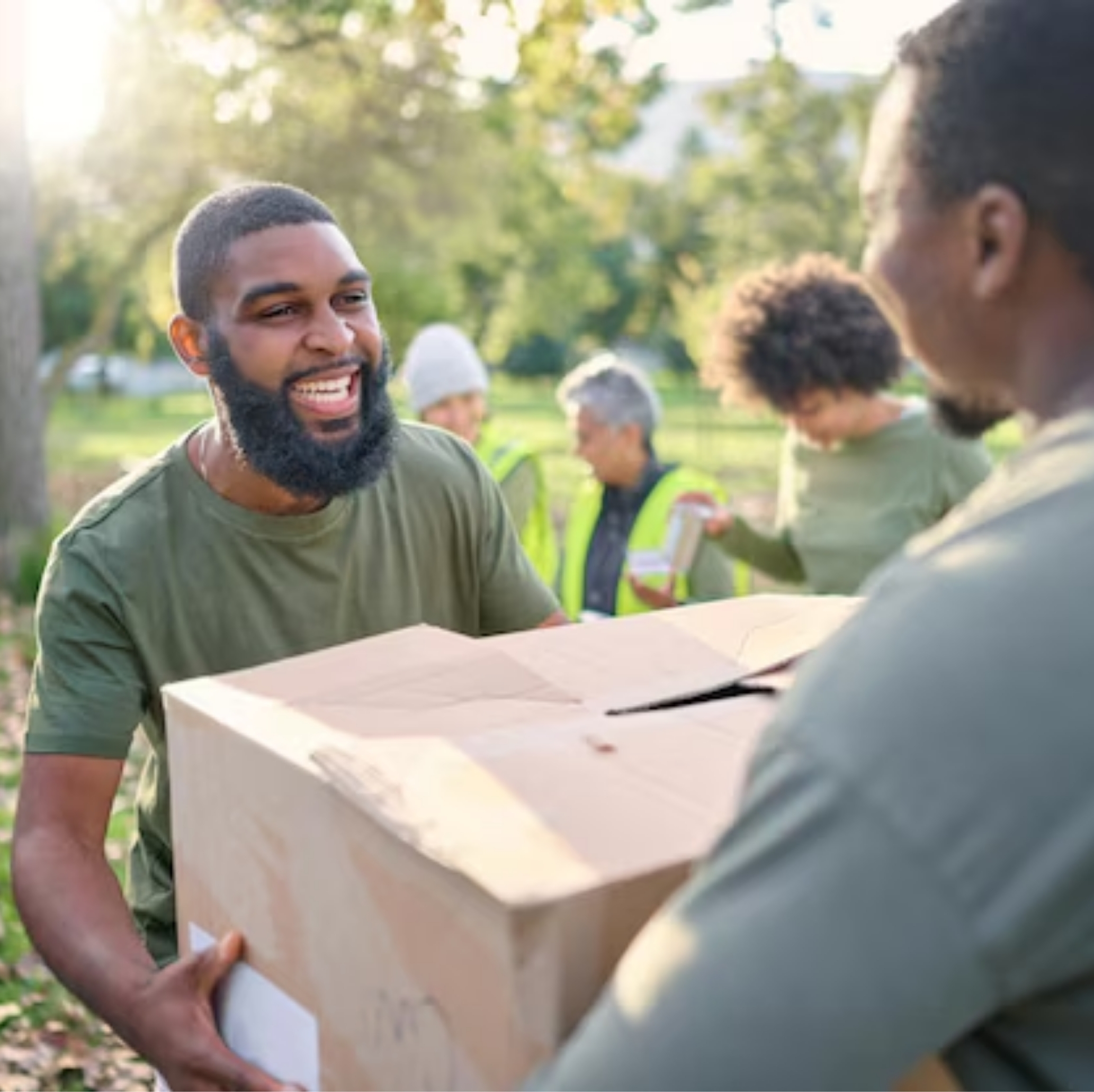 Smiling man carrying a box while helping in a community project symbolising teamwork inclusivity and everyday connection