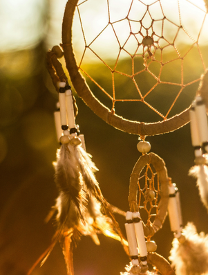 Close-up of a dreamcatcher with feathers glowing in warm sunlight, symbolising dreams and aspirations.