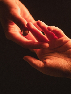 Two hands gently touching in soft light representing the Lover archetype of intimacy and connection