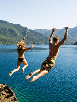 Couple jumping into a lake together representing the Lover archetype of passion and shared experience