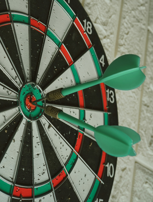 Three darts perfectly hitting the bullseye on a dartboard, symbolising precision and achievement.