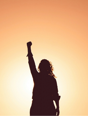 Silhouette of a person raising a clenched fist against a glowing sunset sky, symbolising strength and leadership.