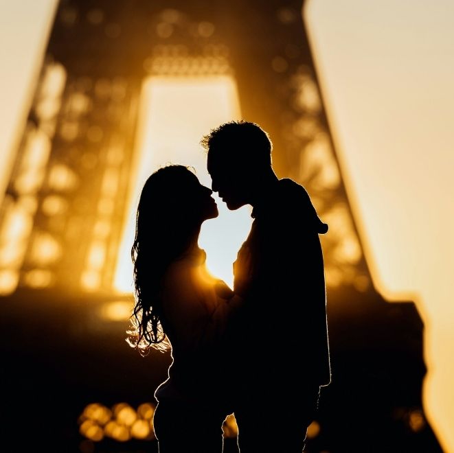 Silhouette of a couple kissing in front of the Eiffel Tower at sunset, symbolising romance and passion.