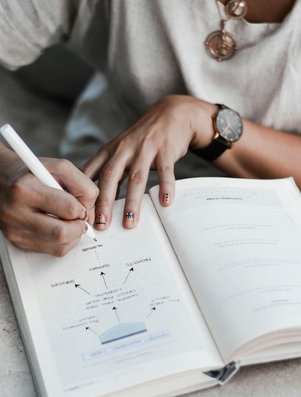 Close-up of a person writing in a journal with a diagram, symbolising planning, reflection, and aspiration.