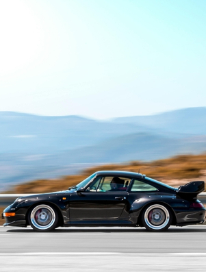 Luxury black sports car driving on an open road representing the Ruler archetype of control and authority