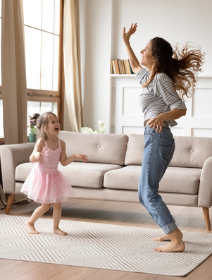 Mother and daughter dancing together at home representing the Jester archetype of playfulness and joy