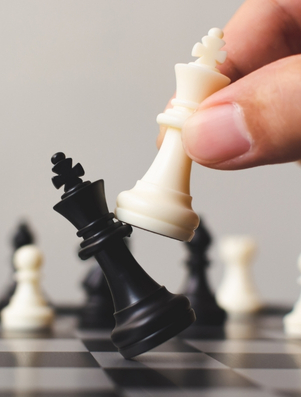 Hand moving a white chess piece to win over a black king representing the Explorer archetype of risk and discovery