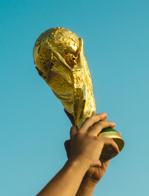 Hands lifting a golden trophy high into the sky, symbolising victory and achievement.